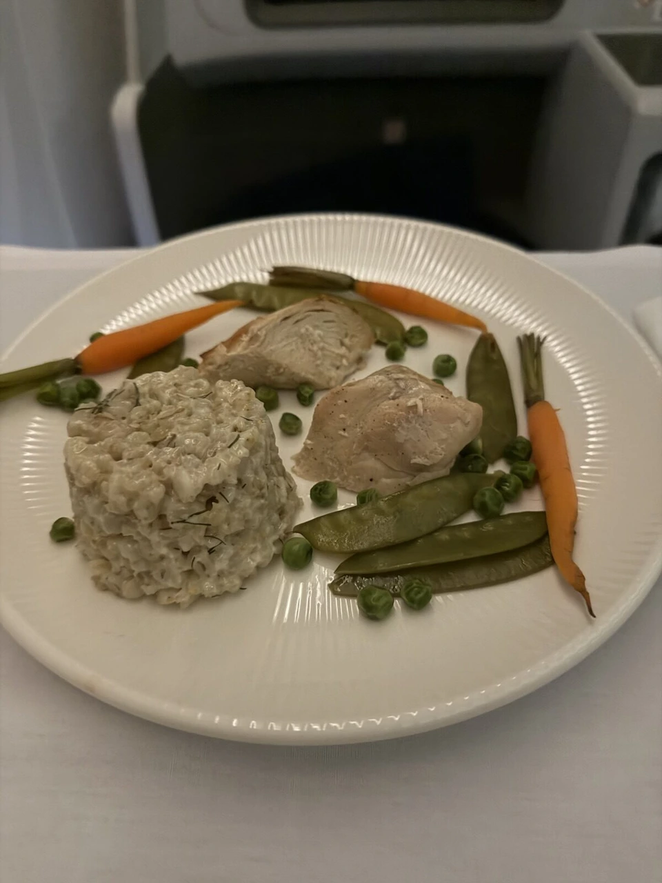 LO79ビジネスクラスのメイン。鶏肉に麦のような付け合わせ、にんじん、さやえんどう、グリーンピース