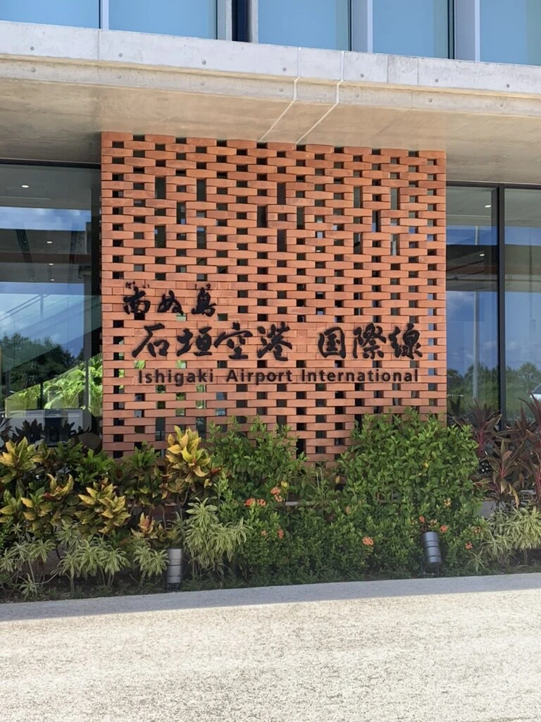 花ブロックの赤い壁の「南ぬ島 石垣空港 国際線」のサイン