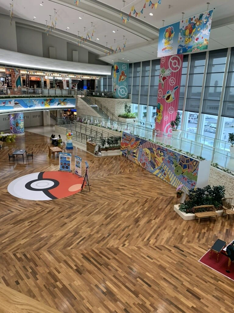 那覇空港の吹き抜けのフロア。床にモンスターボールの模様、壁にポケモンの装飾