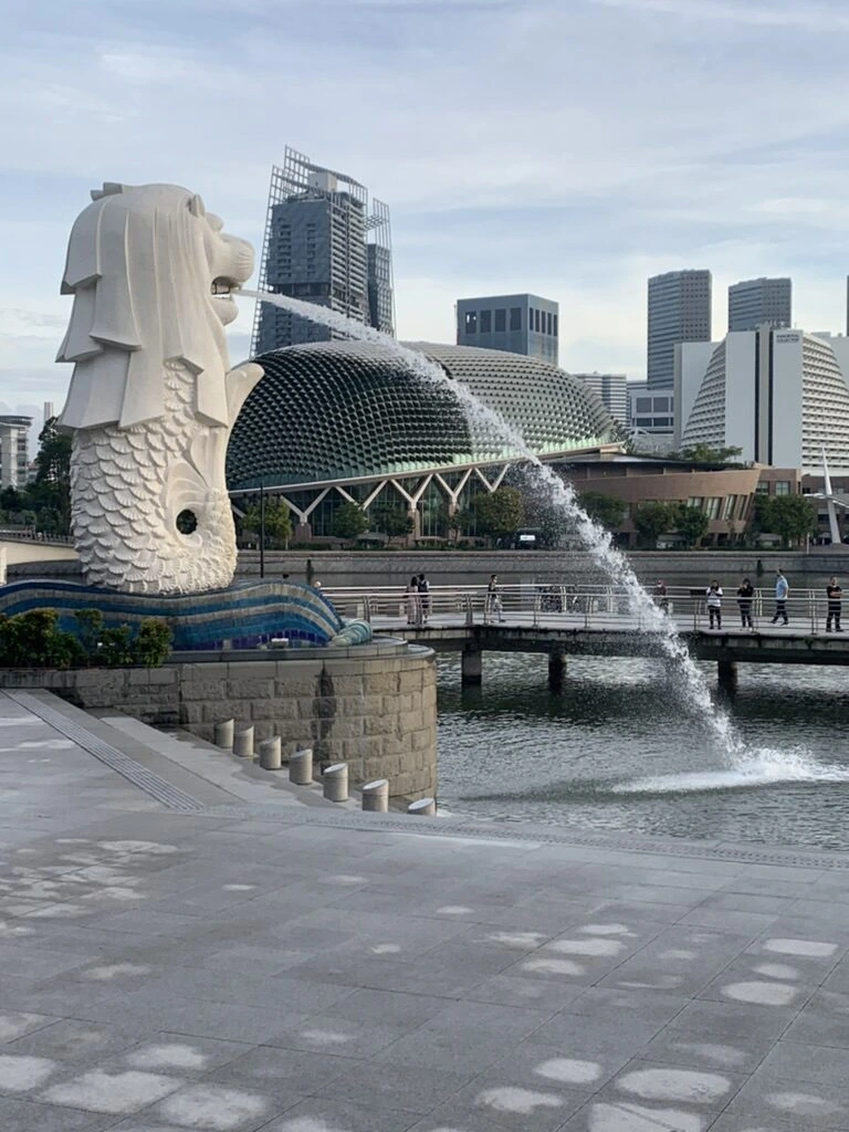 朝のマーライオン公園。マーライオンの口から水が出ていて、奥にビル群