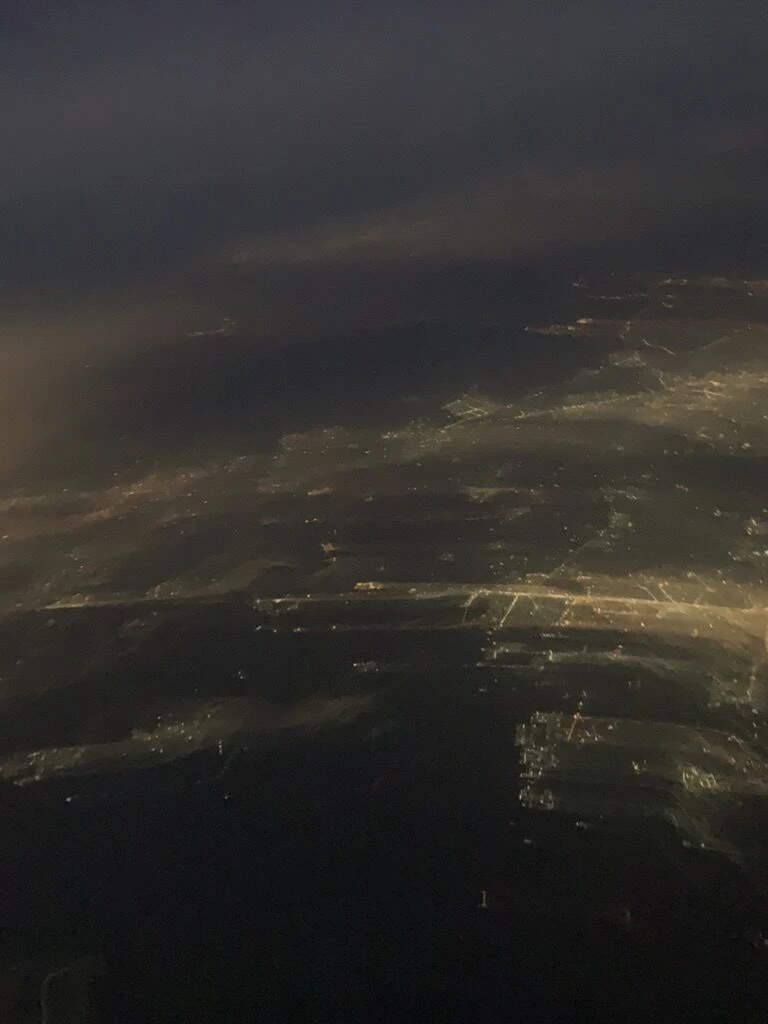 夜の機窓から見た雲の下の街の明かり
