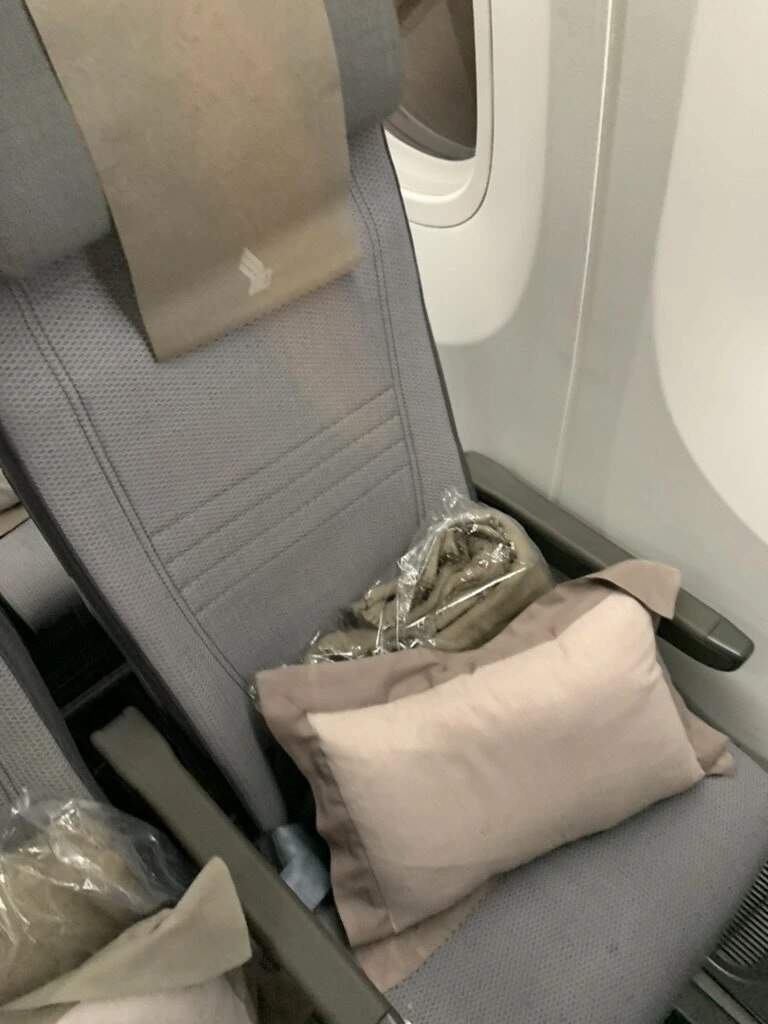 SQ623(787-10)の窓側のエコノミー座席。枕とビニール袋入りの毛布が置いてある
