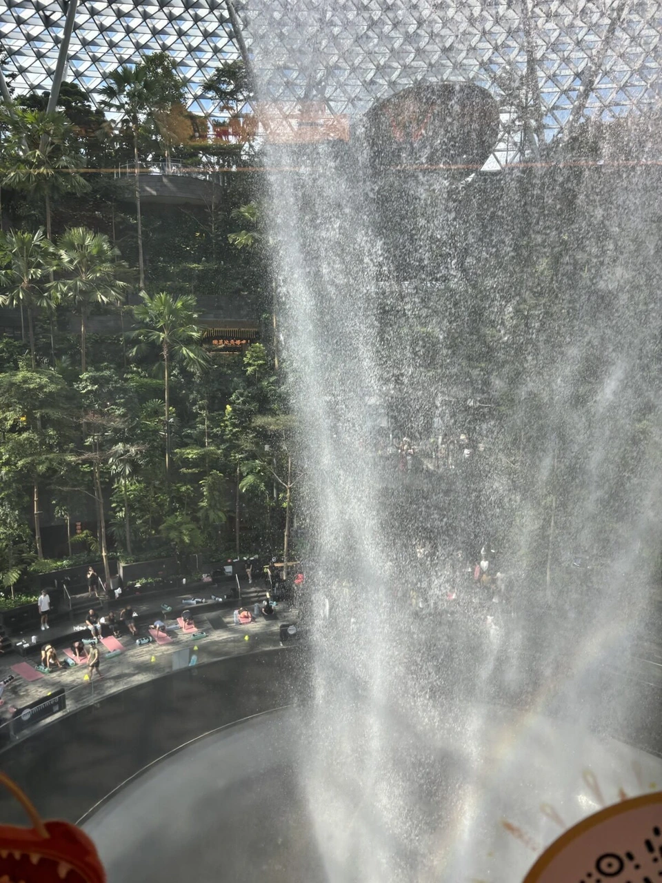 ガラス越しに見たジュエルの屋内の滝。上から水が円形の穴へ落ちている