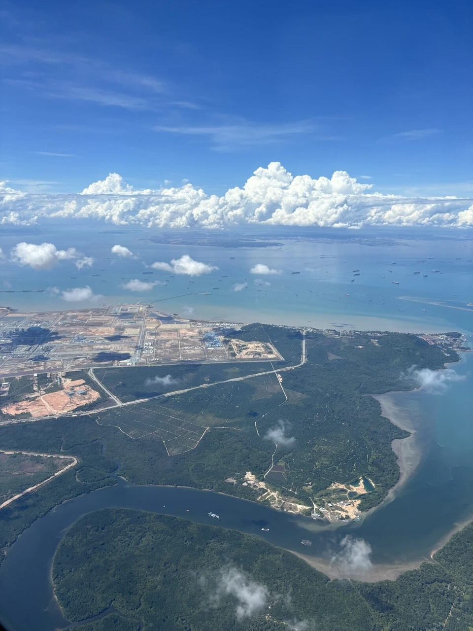 離陸後の機窓から見た島の海岸線と海、遠くに積乱雲
