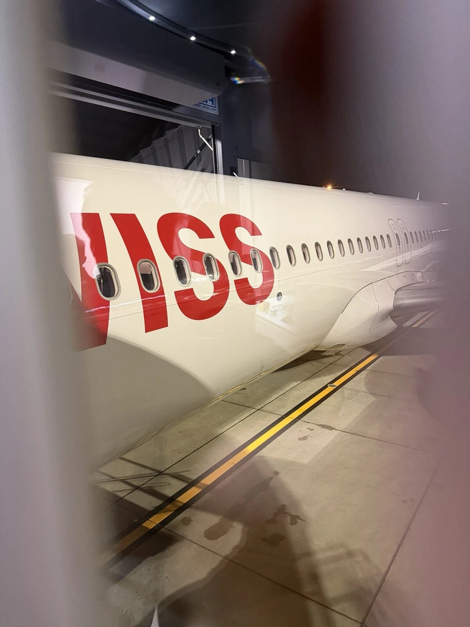 プラハ空港の搭乗橋の窓越しに見た、SWISSの赤い文字が入った機体の胴体