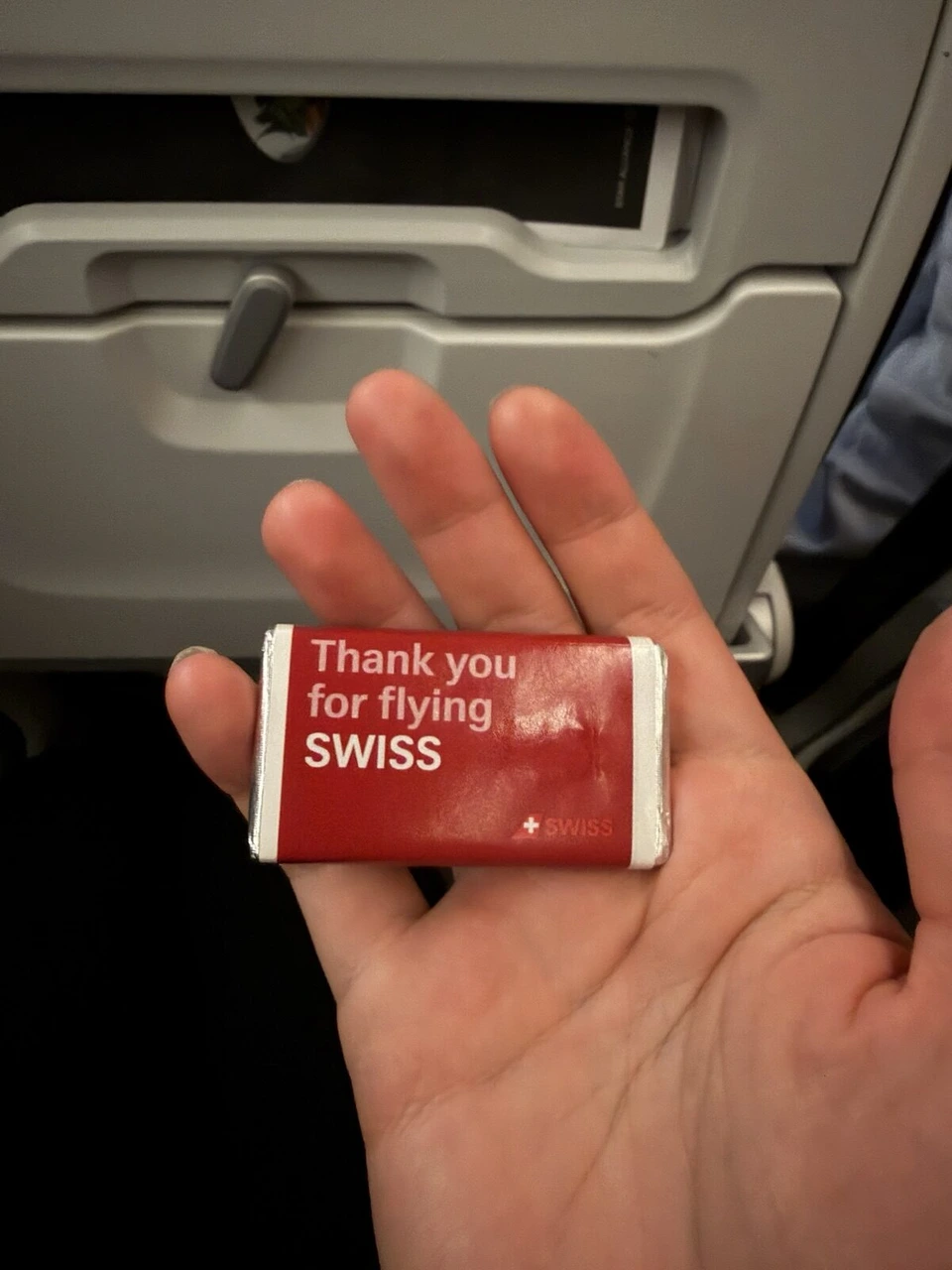 手のひらにのせた、Thank you for flying SWISSと書かれた赤い包みの小さなチョコレート