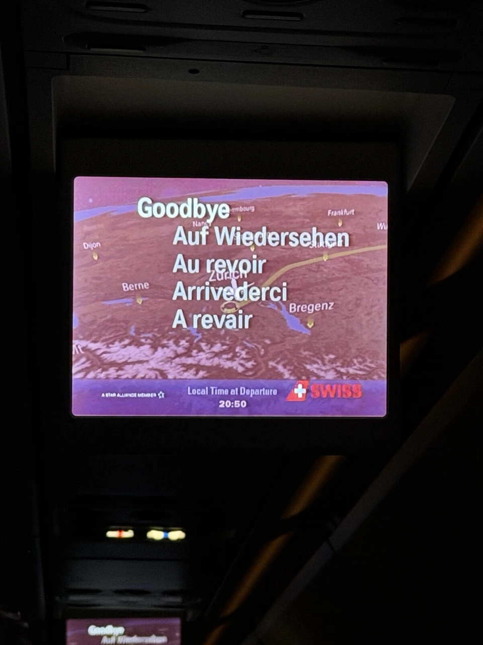 機内のモニターに、Goodbye、Auf Wiedersehen、Au revoir、Arrivederci、A revairの文字とスイスの地図