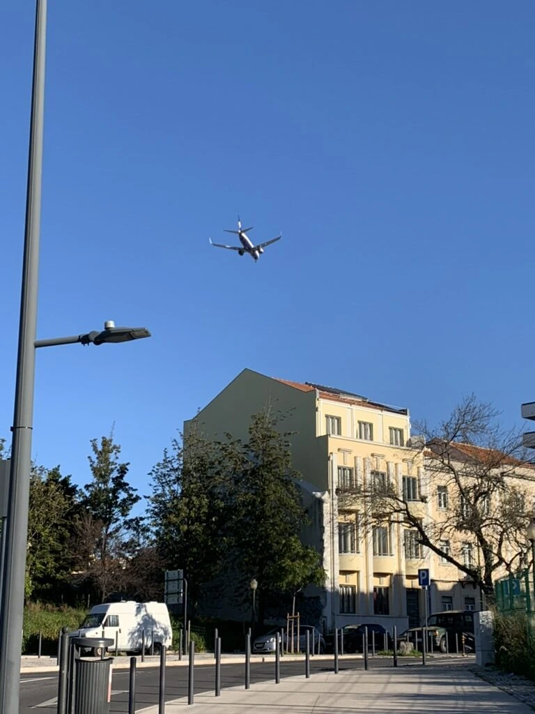 リスボン市内の青空を低く飛ぶ旅客機と建物