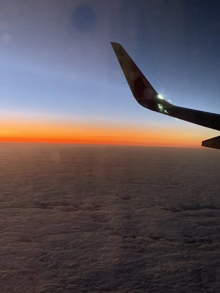 TP1364の機窓から見た雲海の上のオレンジ色の夕焼けとTAP機のウィングレット