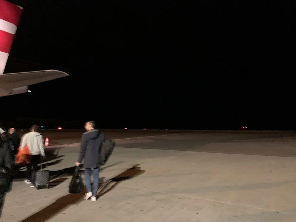 駐機場を歩いて機体へ向かう乗客の後ろ姿