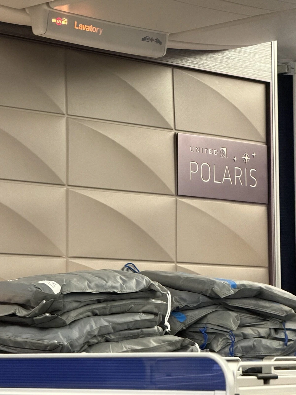 前方ギャレーの壁のUNITED POLARISのサインと、L・XLのパジャマの袋