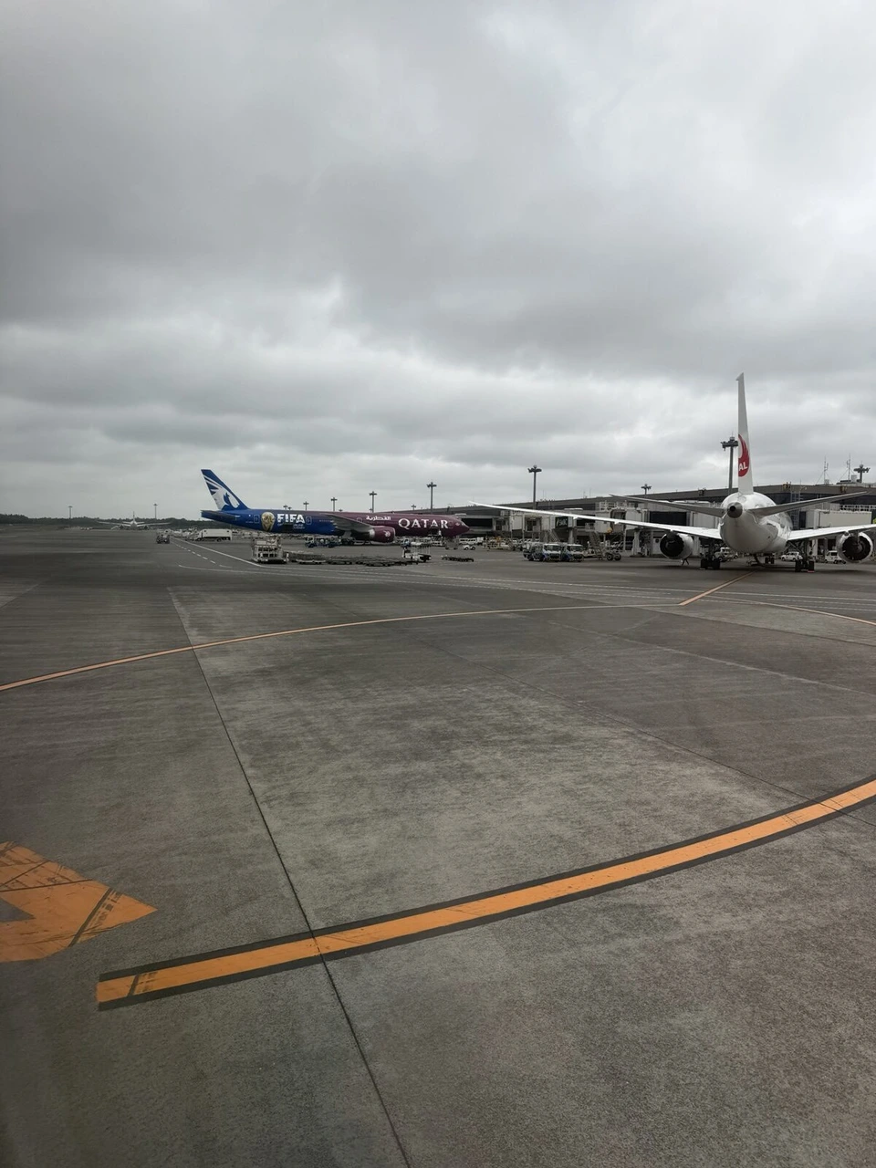 成田空港を地上走行中の機内から見た、サッカーの塗装のカタール航空機とJAL機