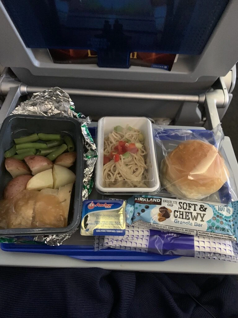 UA177の機内食。チキンとじゃがいもといんげん、トマト入りのパスタサラダ、パン、バター、グラノーラバー