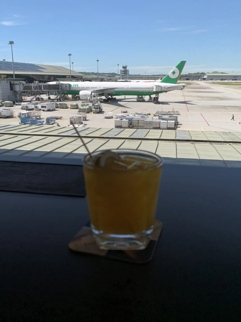 窓際のテーブルに置いたオレンジ色のアイスドリンク。奥にEVA航空機