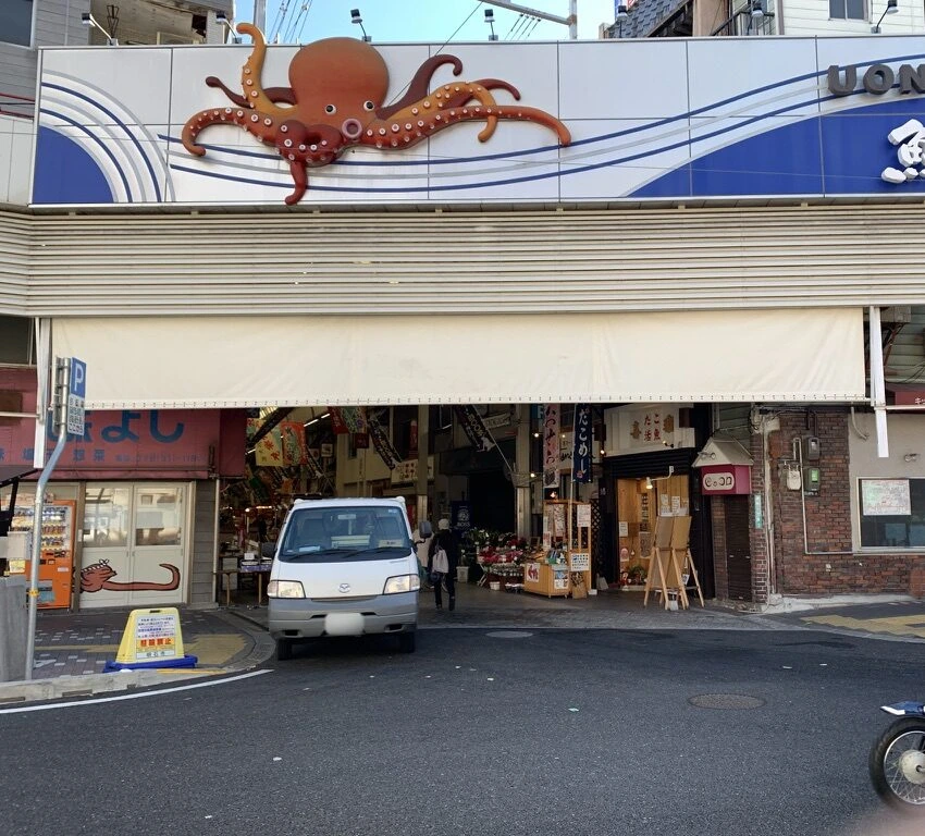 魚の棚商店街の入口の上に付いた大きなタコの飾りと、アーケードの中の店