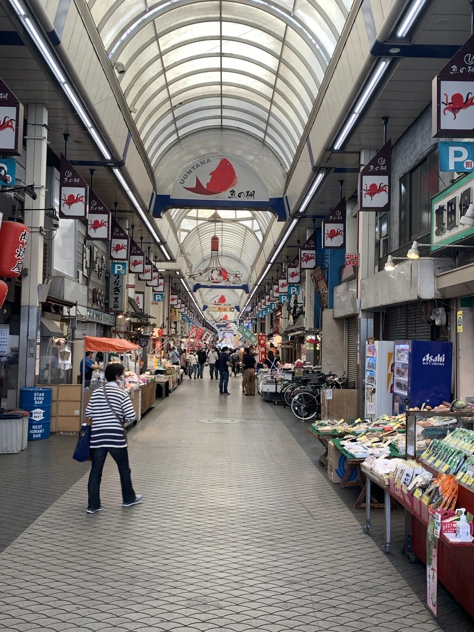 魚の棚商店街のアーケード。天井から鯛の絵とうおんたなの看板が下がり、両側に店が並ぶ