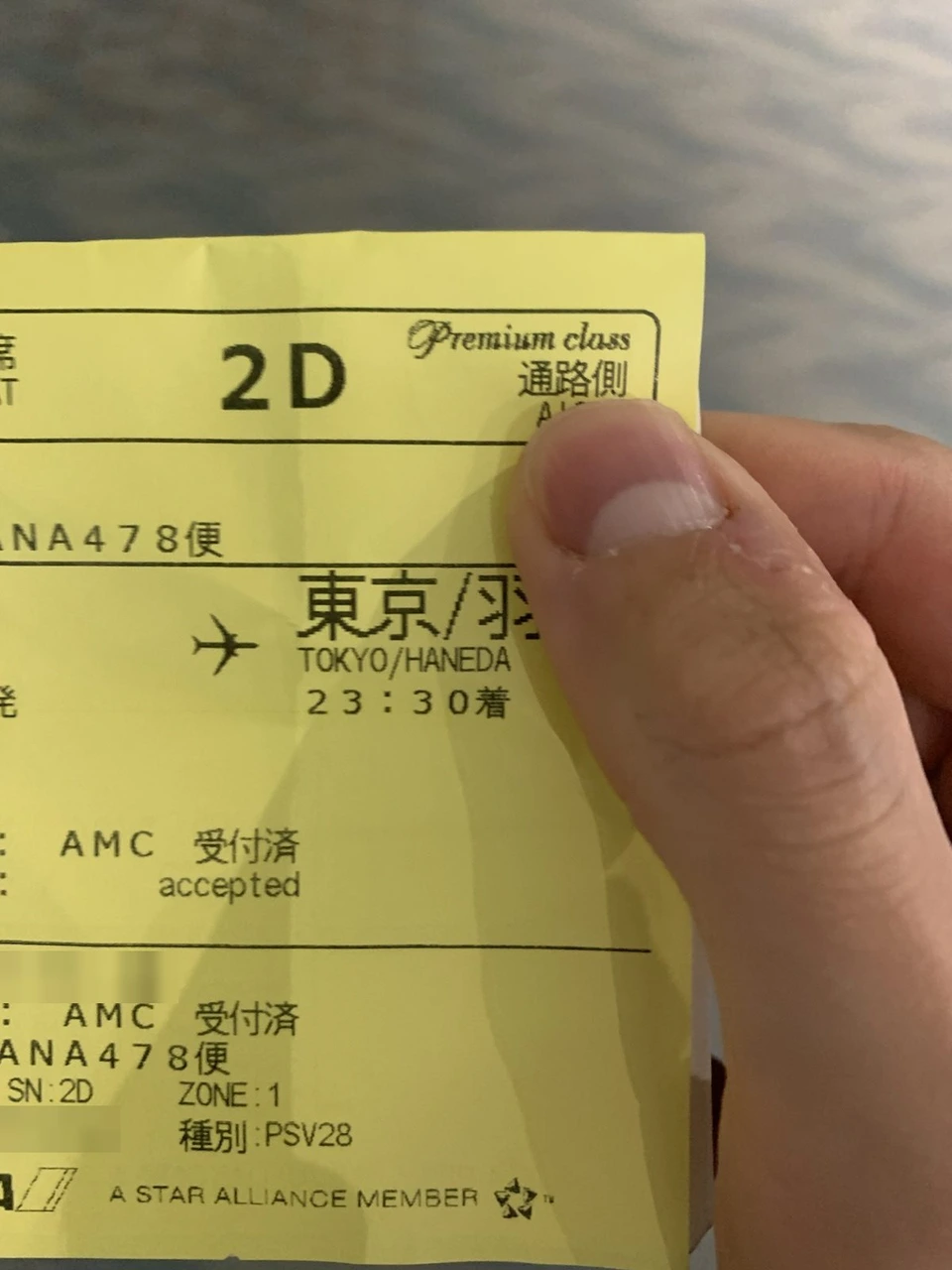 手に持ったNH478の黄色い搭乗券。Premium class、座席2D、通路側