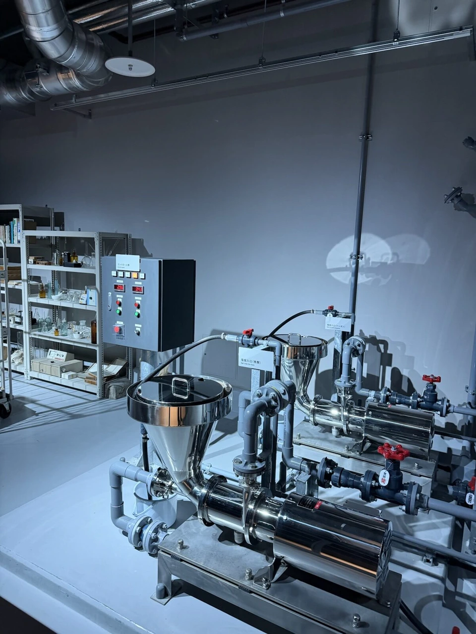 AOAO SAPPORO 4階LABORATORYの、青い光に照らされた海水をつくるプラント。銀色の塩投入口と配管、コントロール盤