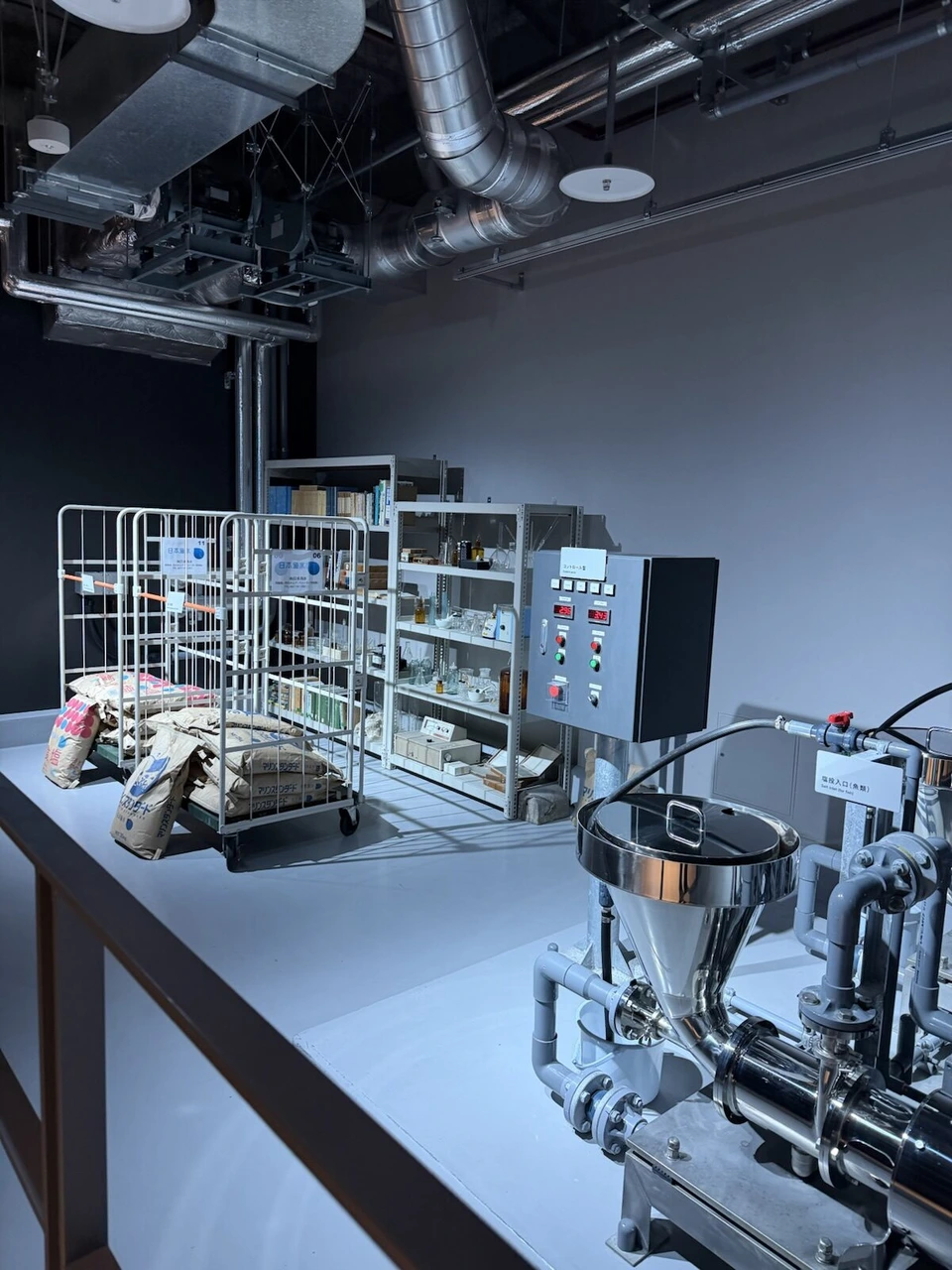 AOAO SAPPOROのLABORATORY。海水をつくるプラントの奥に、塩の袋と棚に並んだ実験器具