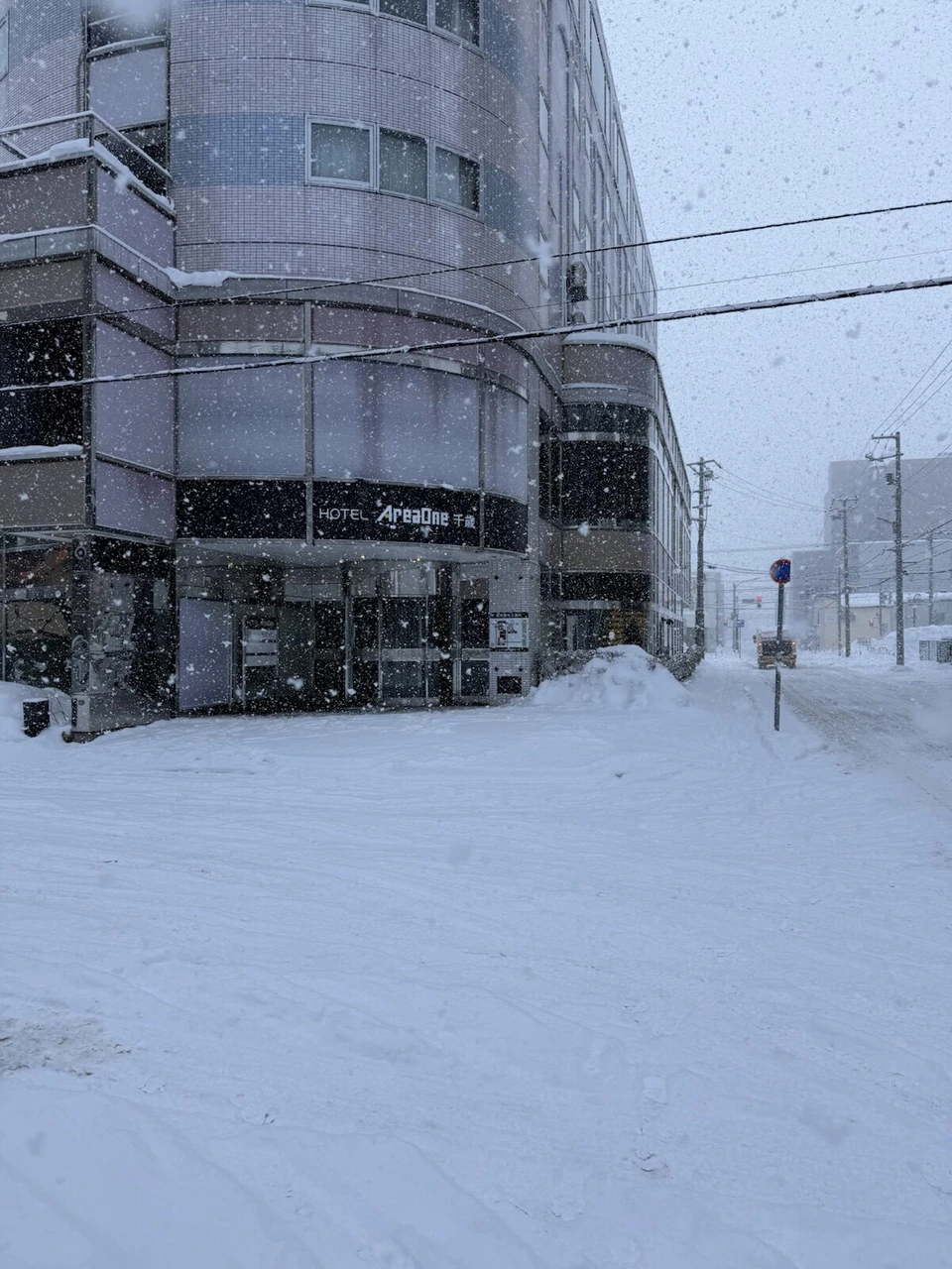 雪が積もった朝の通りと、雪が降り続く街並み