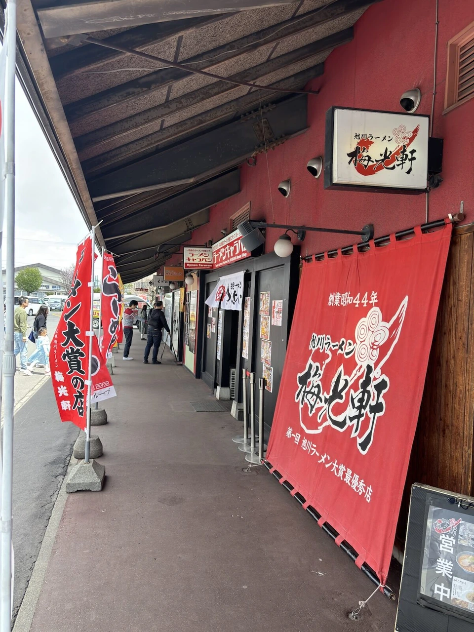 旭山動物園へ向かう道沿いの、赤い外壁にラーメン店が並ぶ建物。梅光軒の大きな暖簾とのぼり
