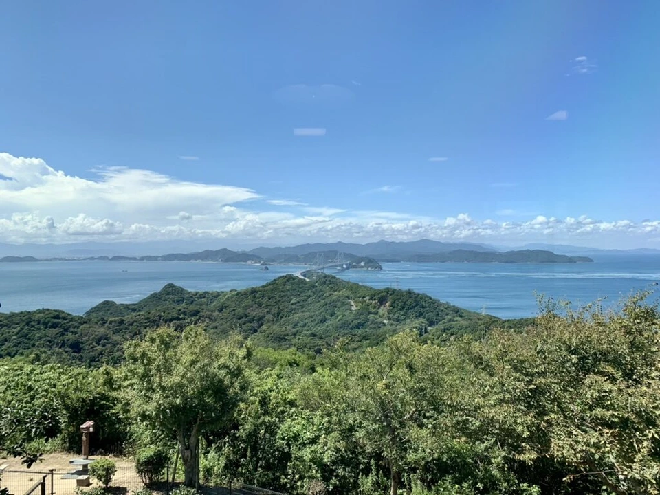うずの丘から見た緑の山の向こうの海と、遠くの島々
