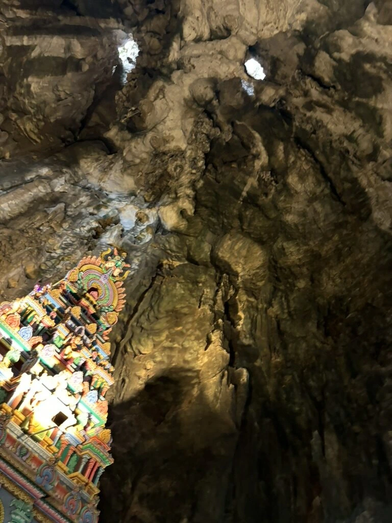 洞窟の岩肌と、照明に照らされた寺院の塔の一部