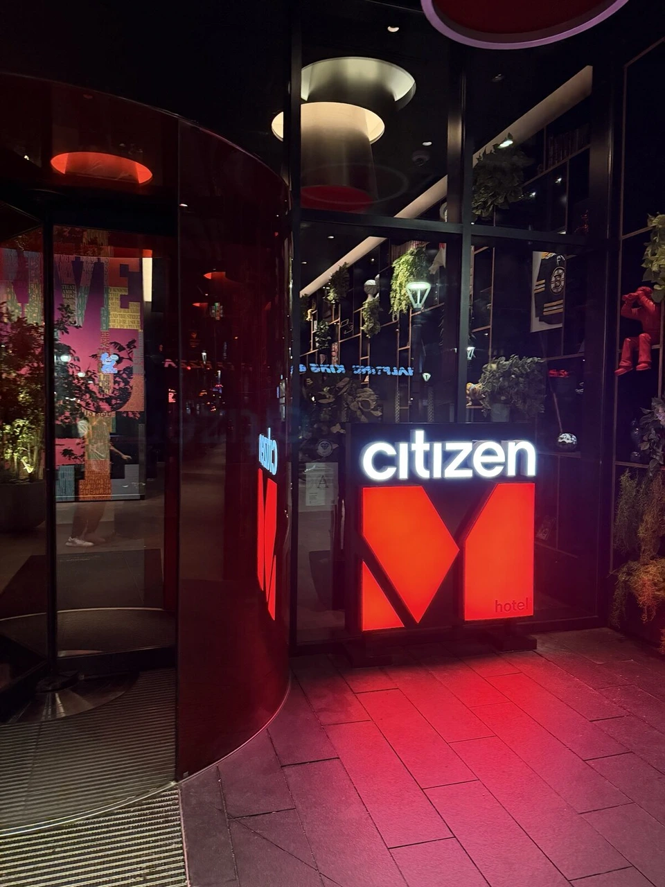 夜のcitizenM Boston North Stationの入口。赤いMのサインと回転ドア
