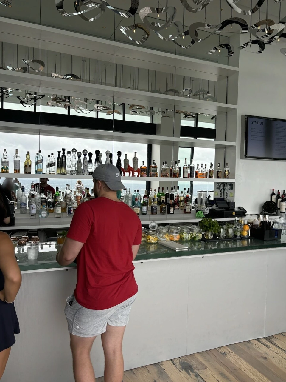 View Bostonのバーカウンター。お酒のボトルが並ぶ白い棚と、天井の金属の飾り