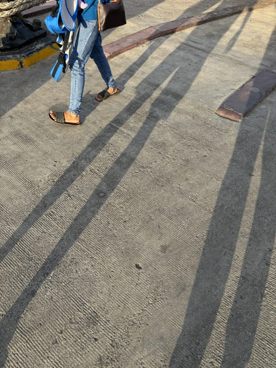 夕方の港の岸壁に伸びる人の長い影