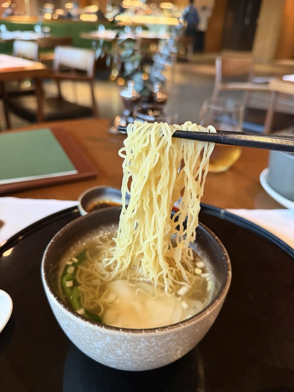 ワンタン麺の細い卵麺を箸で持ち上げたところ