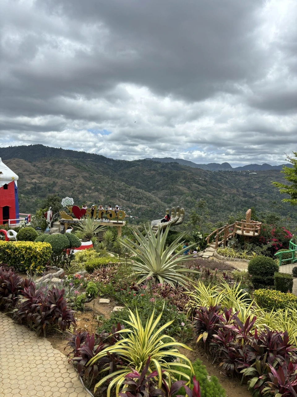 曇り空の下の山並みと、手前の色とりどりの植え込み