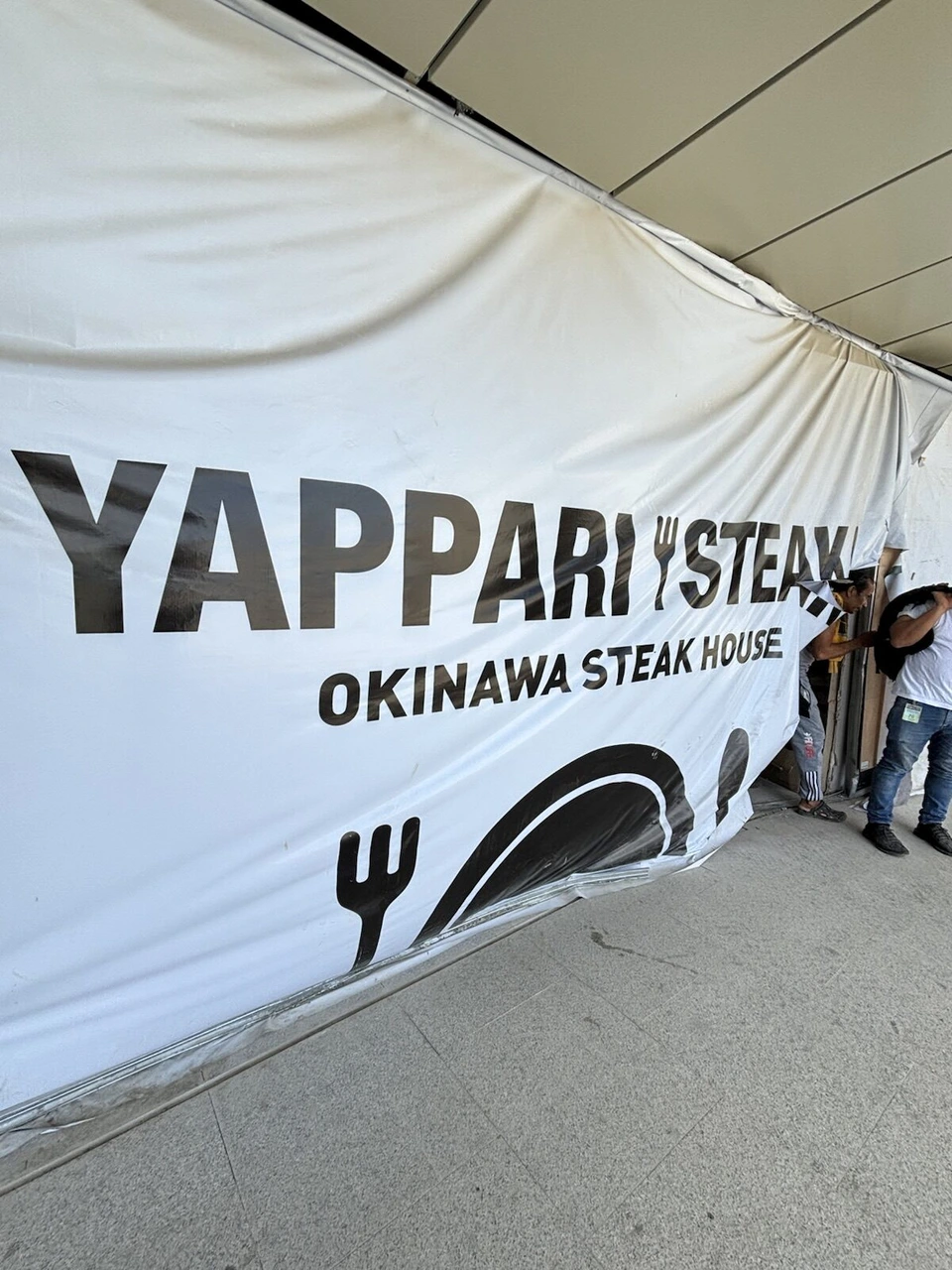 トップス展望台の建物の白い幕に大きく書かれたYAPPARI STEAKとOKINAWA STEAK HOUSEの文字