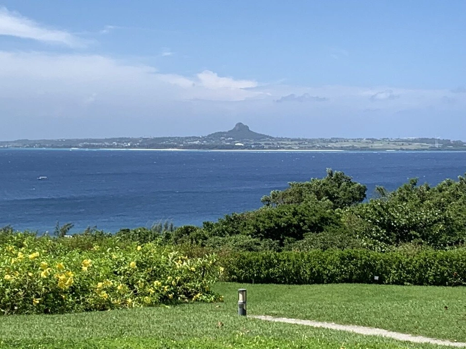 海洋博公園の芝生と黄色い花の植え込みの向こうに広がる海と伊江島