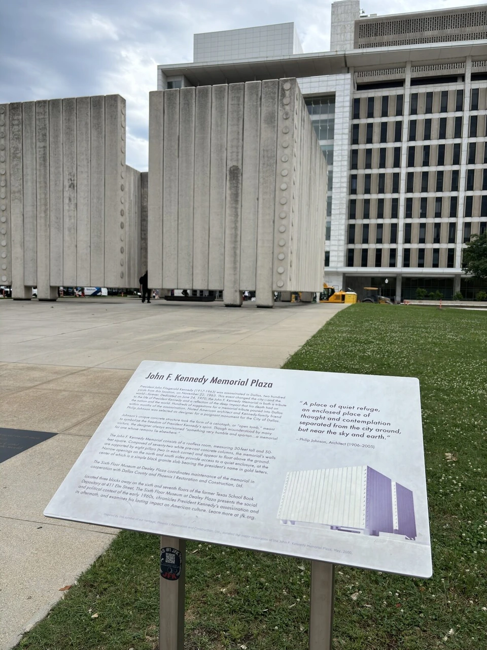 John F. Kennedy Memorial Plazaの説明板と、奥の白いコンクリートの壁