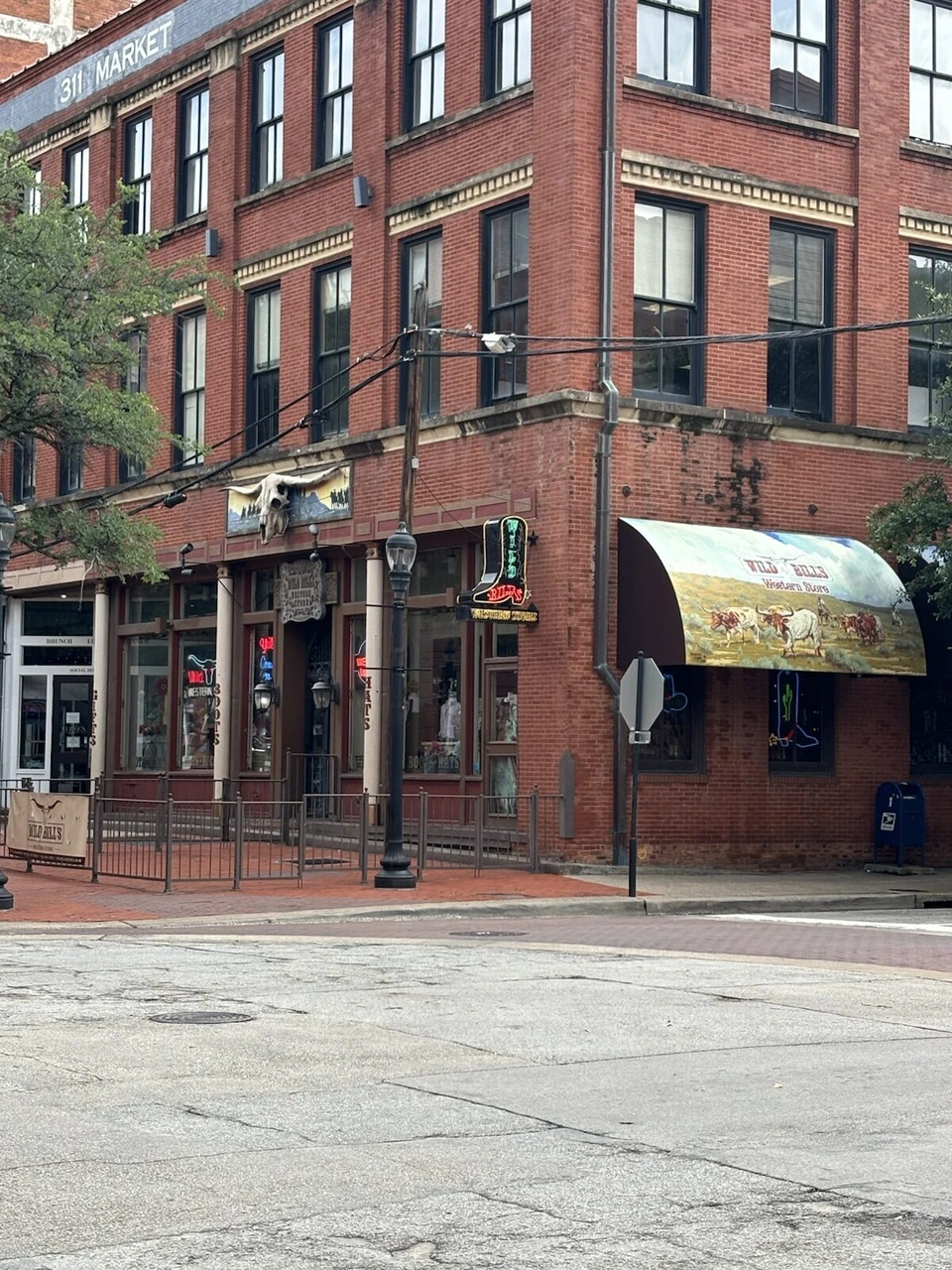 311 MARKETと書かれたれんがのビルと、牛の絵の日よけがあるWild Bill's Western Store