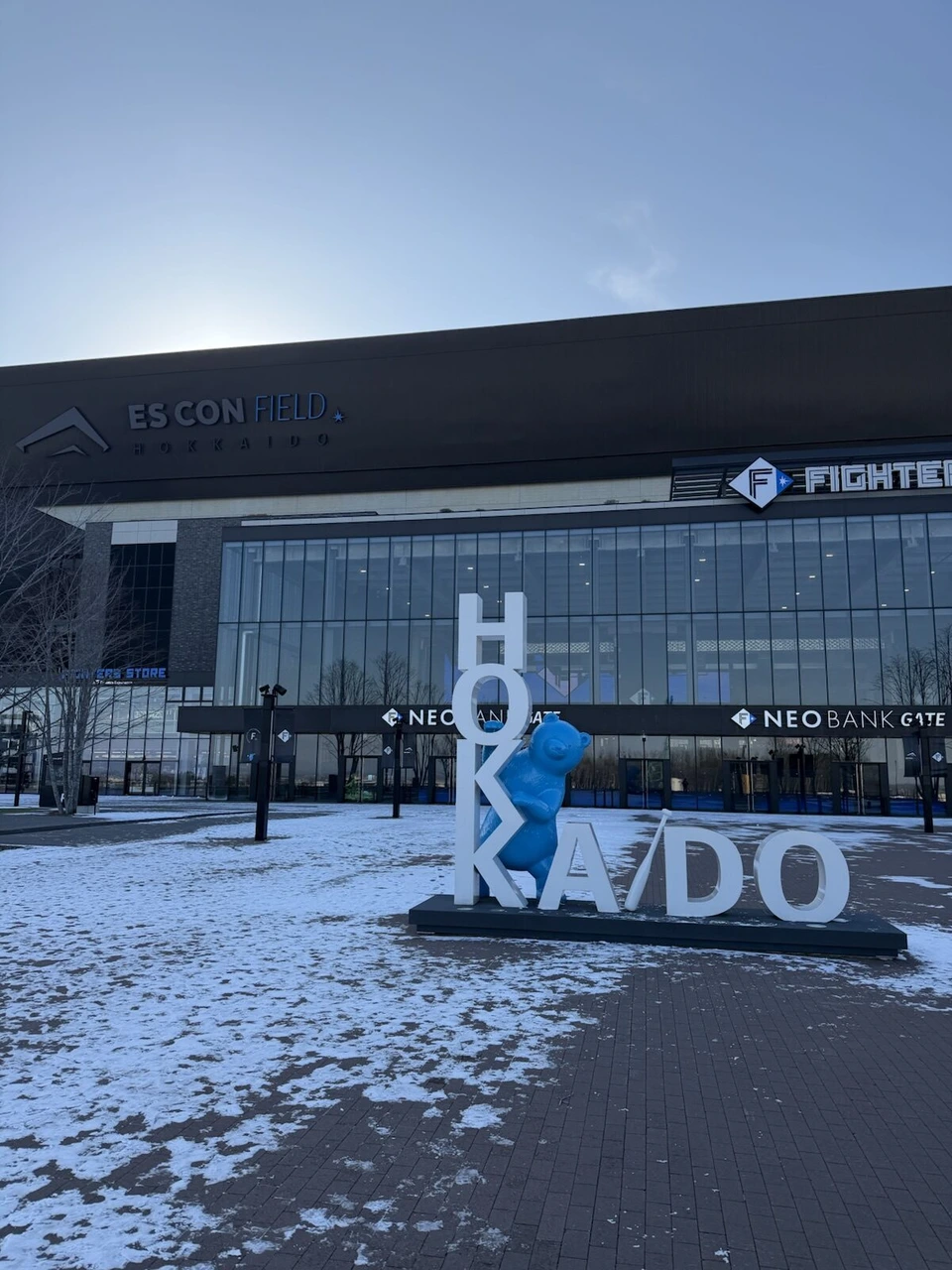 エスコンフィールドHOKKAIDO正面のHOKKAIDOモニュメント。真ん中に青いキャラクターの像、奥にFIGHTERSのロゴとNEOBANK GATE