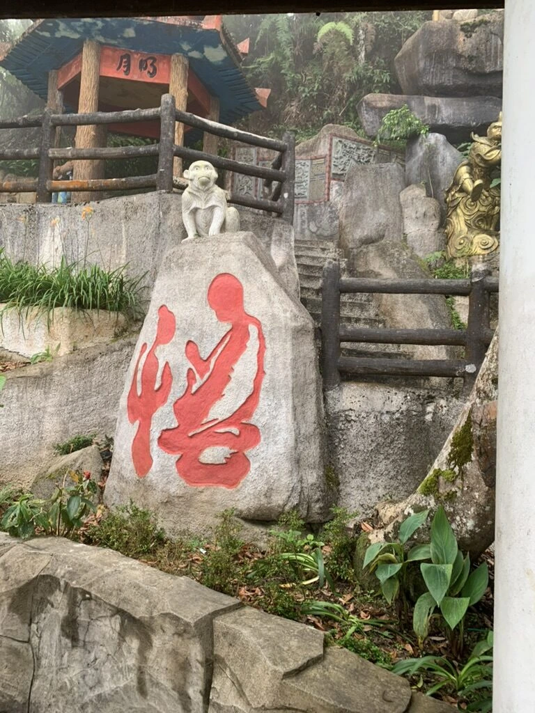 チンスイ洞窟寺院の赤い漢字が彫られた岩と、その上の白い猿の像