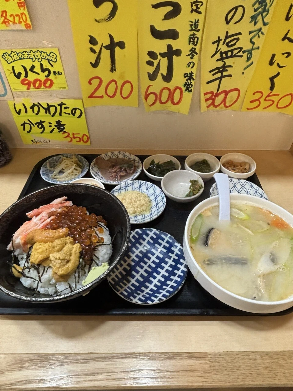 函館朝市で食べた海鮮丼と汁物、小鉢。壁にいか汁やかに汁の値札