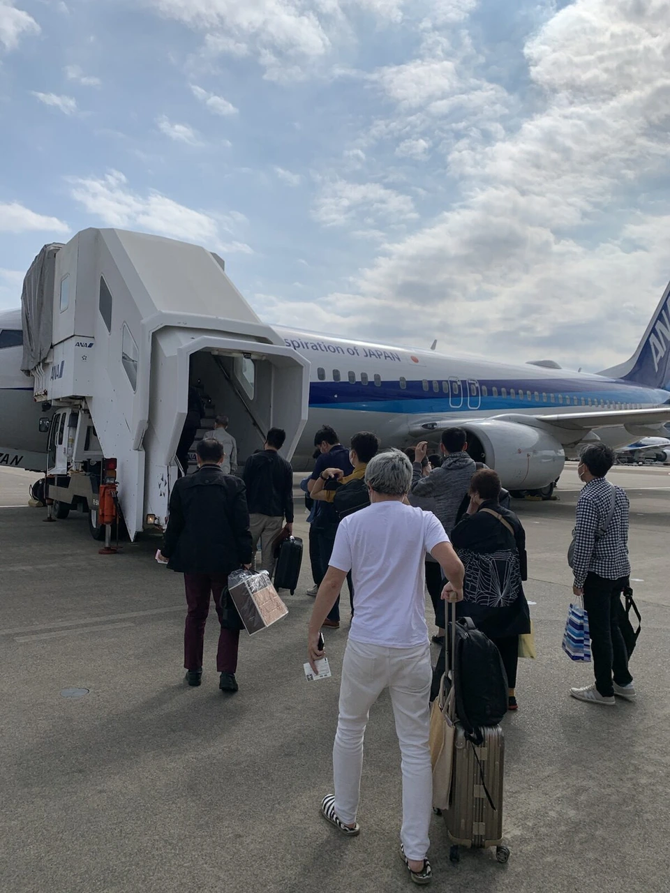 バスを降りてANAのボーイング737-800のタラップへ歩く乗客たちの後ろ姿