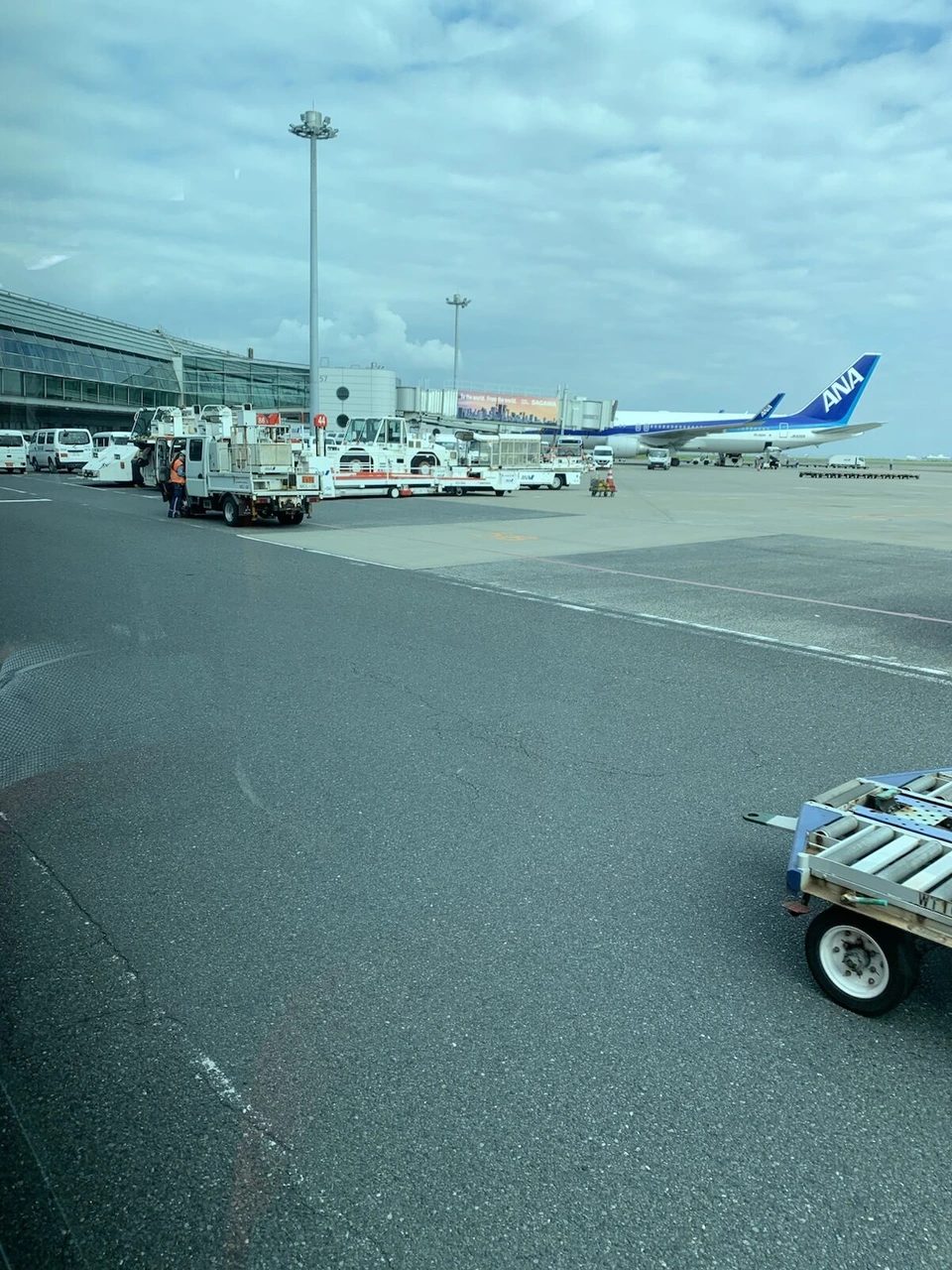 バスの窓から見た羽田空港の駐機場。作業車が並び、奥にANA機が止まっている