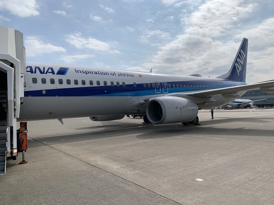 羽田空港の駐機場に止まるANAのボーイング737-800と、前方ドアに付けられた白いタラップ車