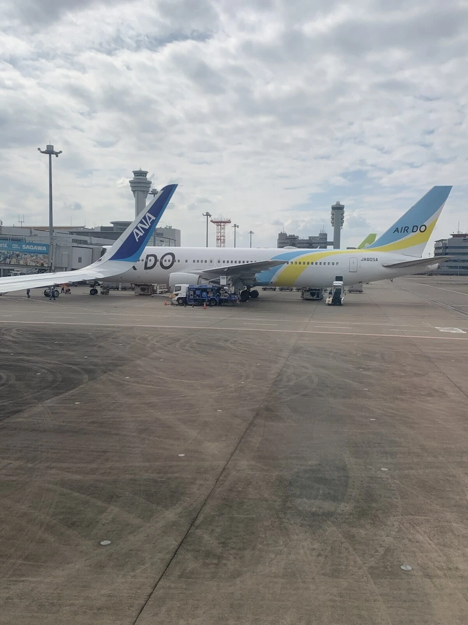 羽田空港に着いたNH22の窓から見た駐機場。AIRDOのボーイング767と、手前にANA機の尾翼、奥に管制塔