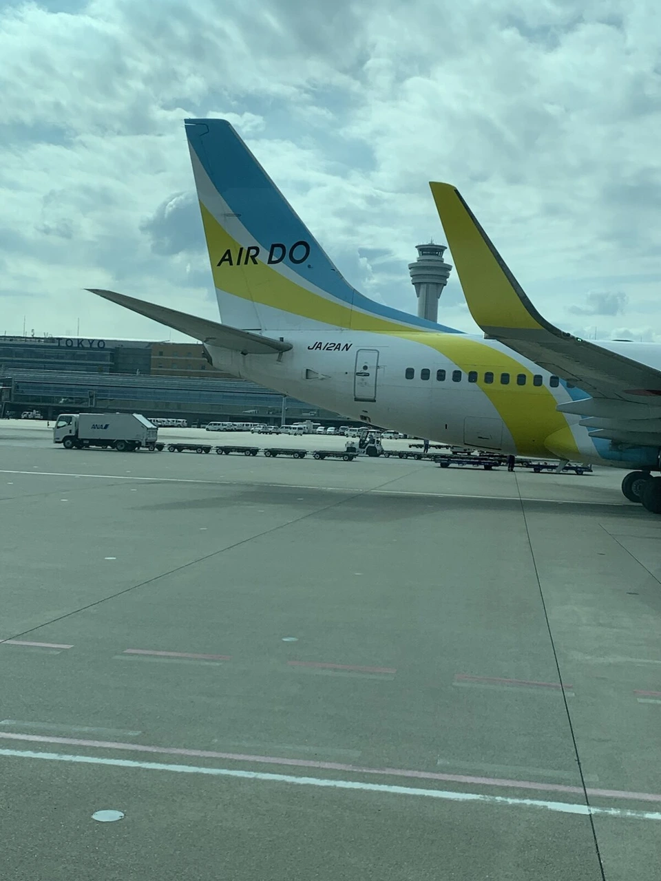 バスの窓から見た2機のAIRDO機の尾翼と、奥に羽田空港の管制塔