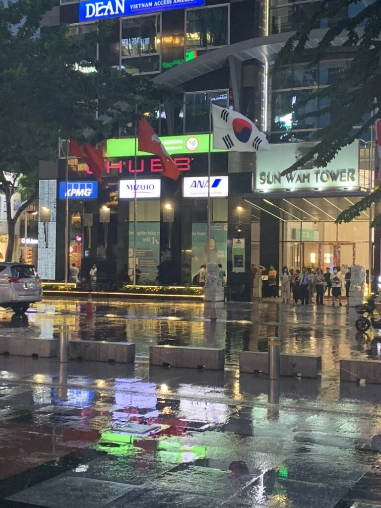 雨に濡れた夜のホーチミンの通りとSun Wah Towerのビル