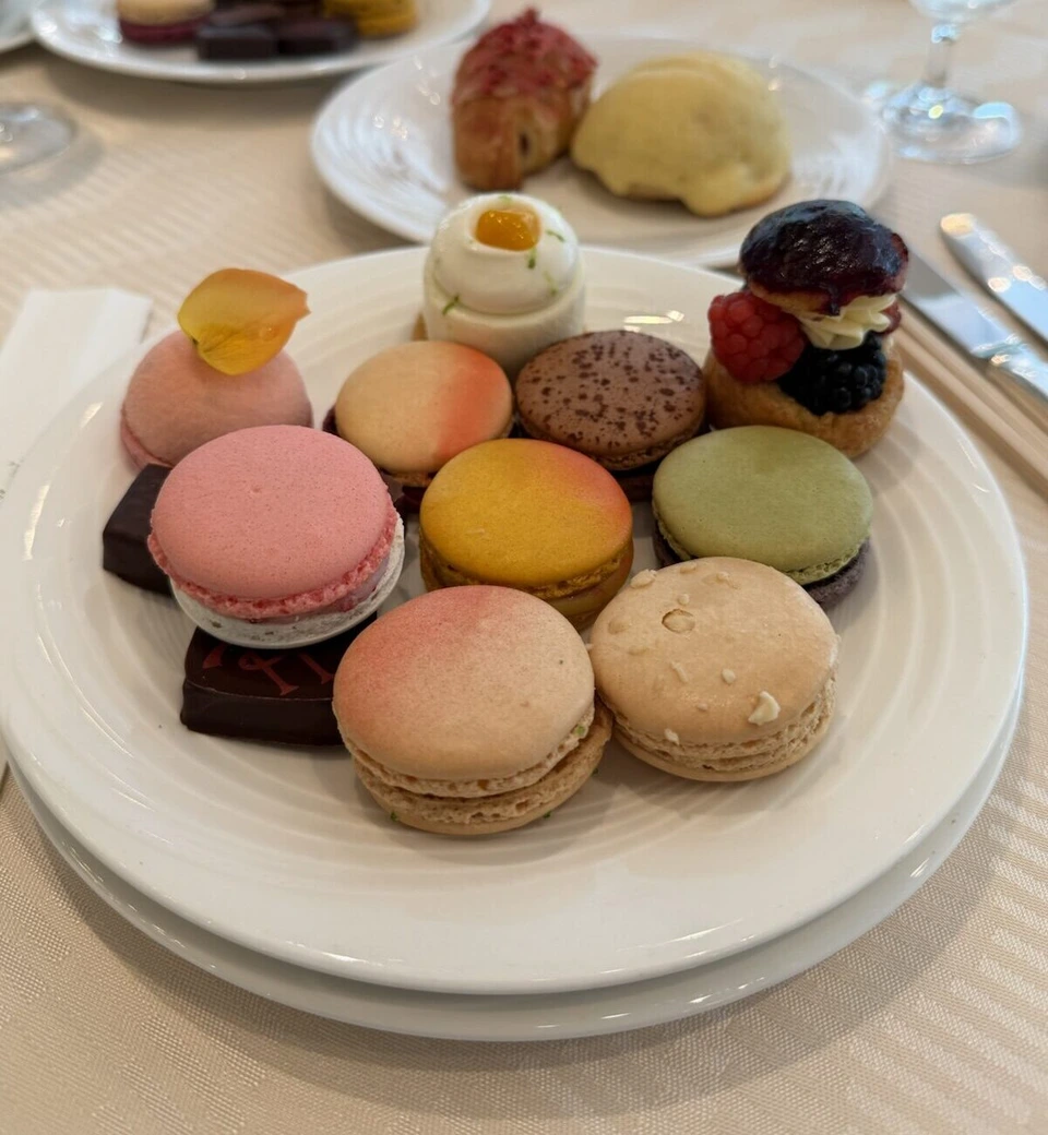 白い皿に盛ったマカロンとチョコレート、ベリーのシュー。奥にパンの皿