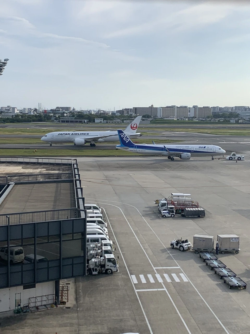 伊丹空港の屋上展望デッキから見た誘導路。JALのボーイング787と、その手前にANAの細長い機体。手前に駐機場と地上の車両