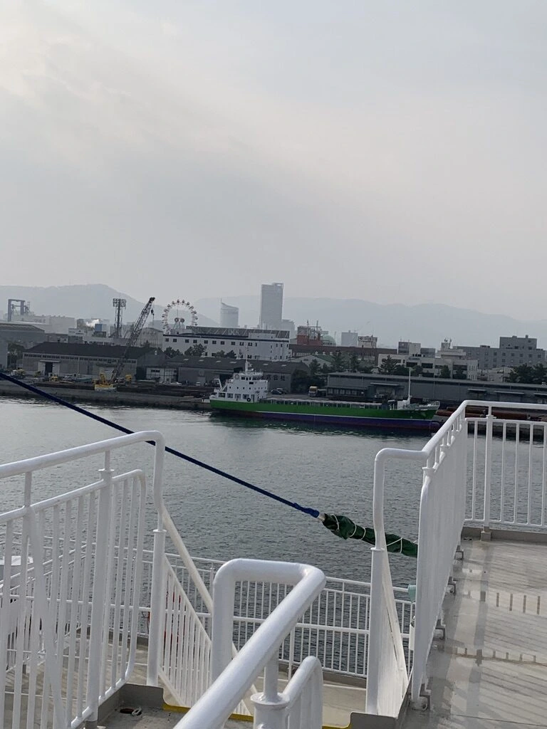 出港直後のジャンボフェリーのデッキから見た高松東港。岸壁に緑の船、奥に観覧車とビル