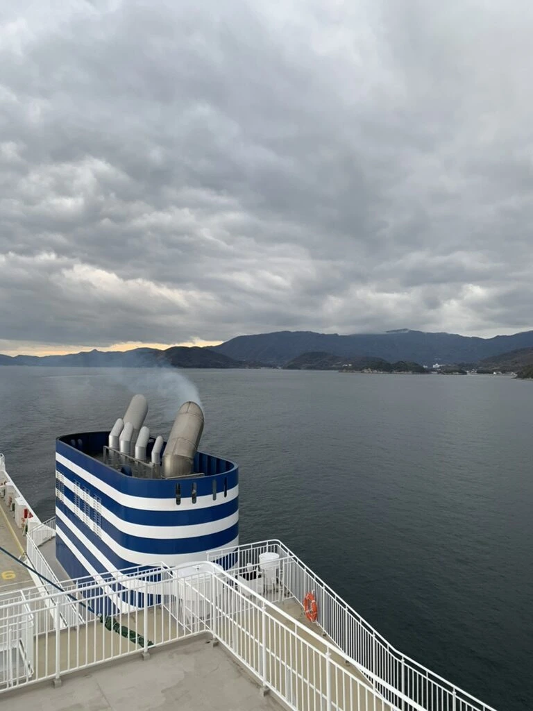 青白の縞の煙突から煙が出ている。奥に山並み