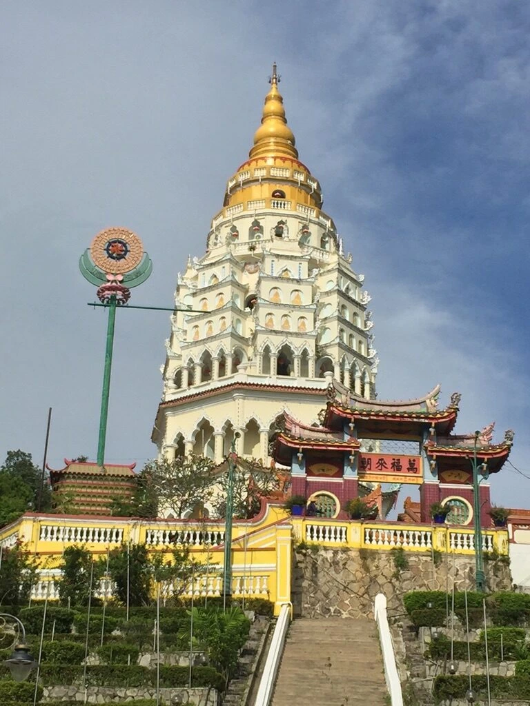 青空の下の極楽寺の白い仏塔(万仏塔)と手前の中華風の門